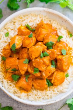 A bowl of chicken tikka masala served over white rice, garnished with fresh cilantro.