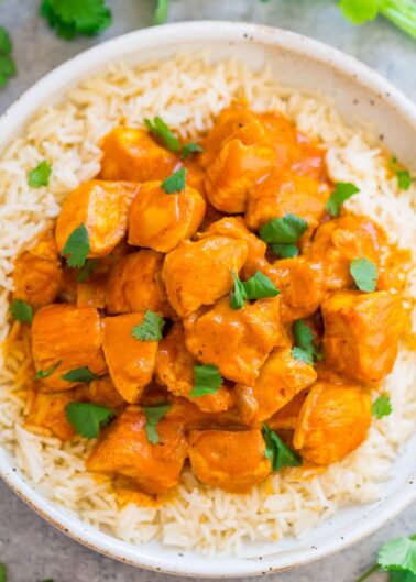 A bowl of chicken tikka masala served over white rice, garnished with fresh cilantro.