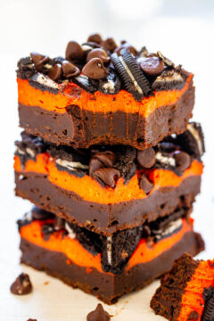 A stack of chocolate brownies with orange cream filling and topped with chocolate chips and cookie pieces.