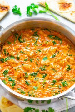 A creamy tomato-based curry dish with spinach, garnished with coriander, served in a pan.