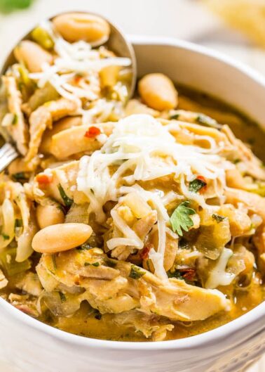 A bowl of white bean chicken chili topped with shredded cheese.