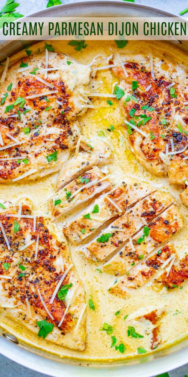 Cooked chicken breasts in a creamy parmesan Dijon sauce, garnished with chopped parsley and grated cheese, in a pan.