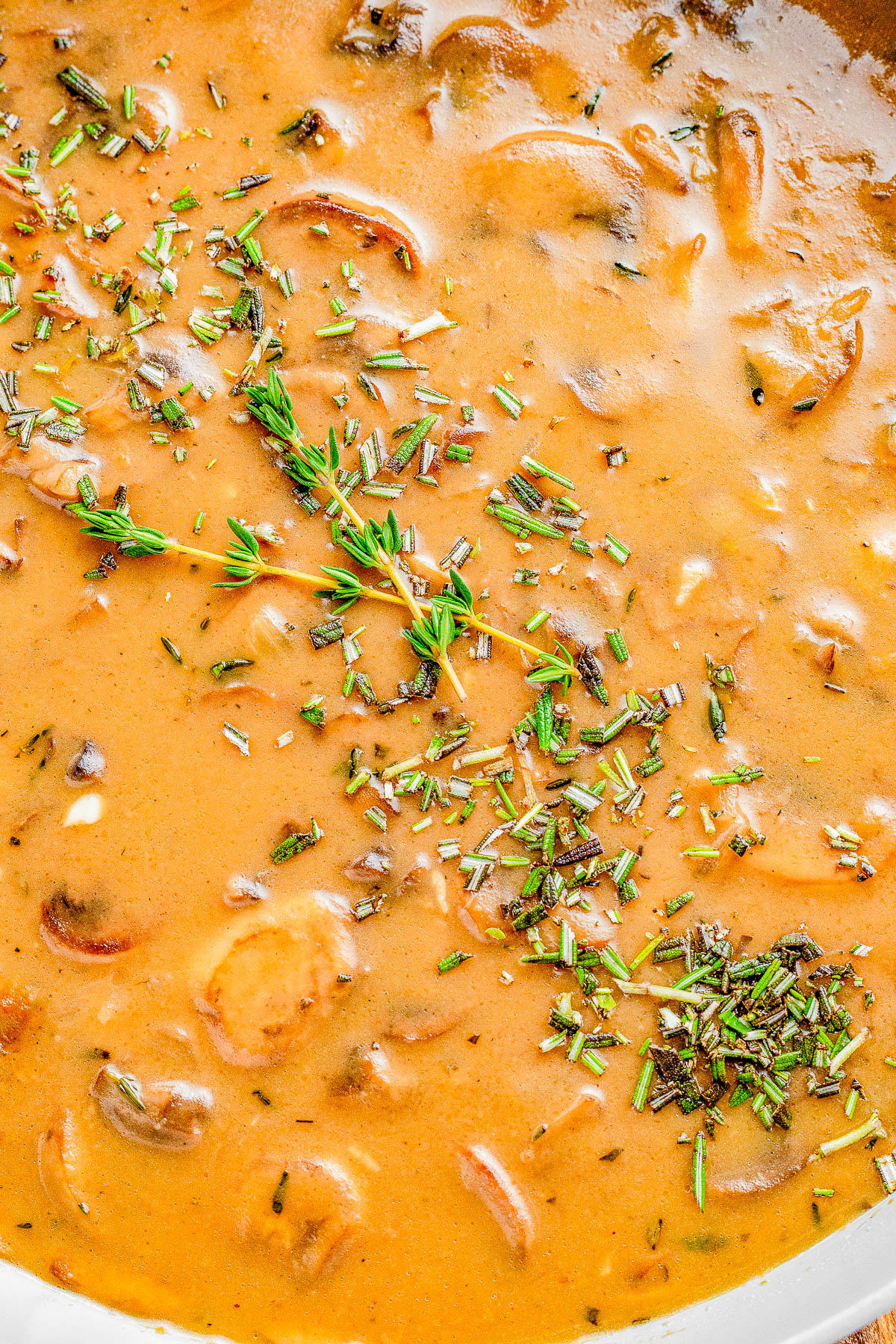 Close-up of creamy mushroom sauce with chopped herbs.

.