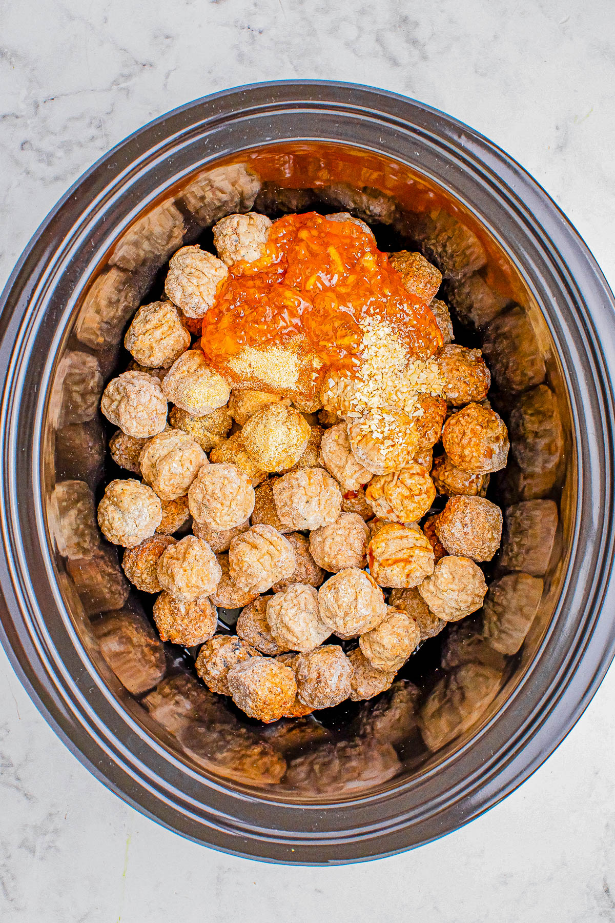 Crockpot filled with meatballs topped with sesame seeds and viewed from above.