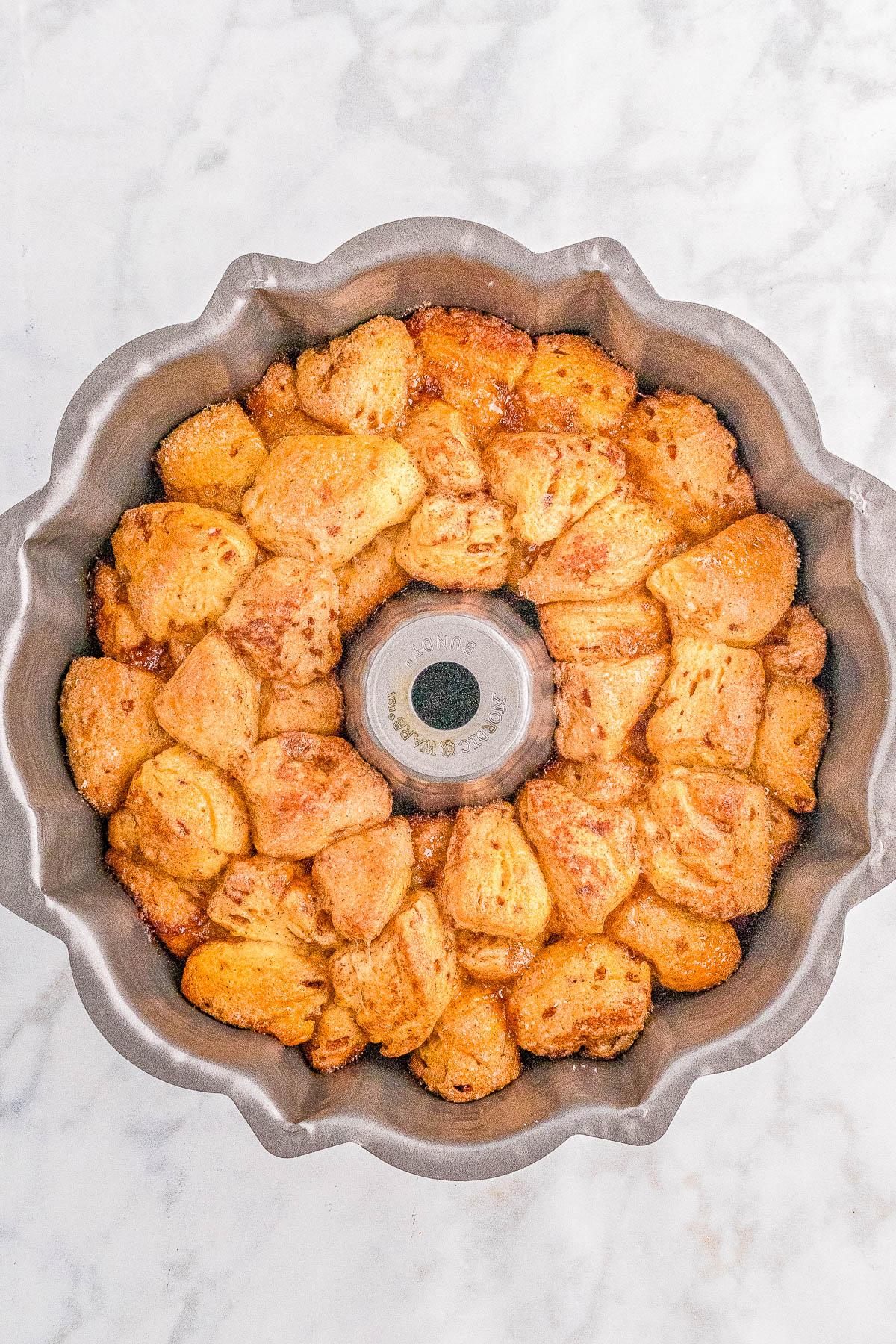 Freshly baked monkey bread in a Bundt pan on a marble surface.