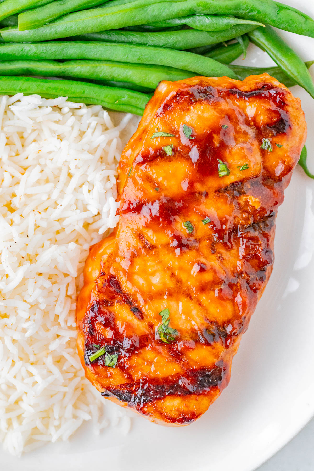 Grilled pork chops with a glaze, served with white rice and green beans.