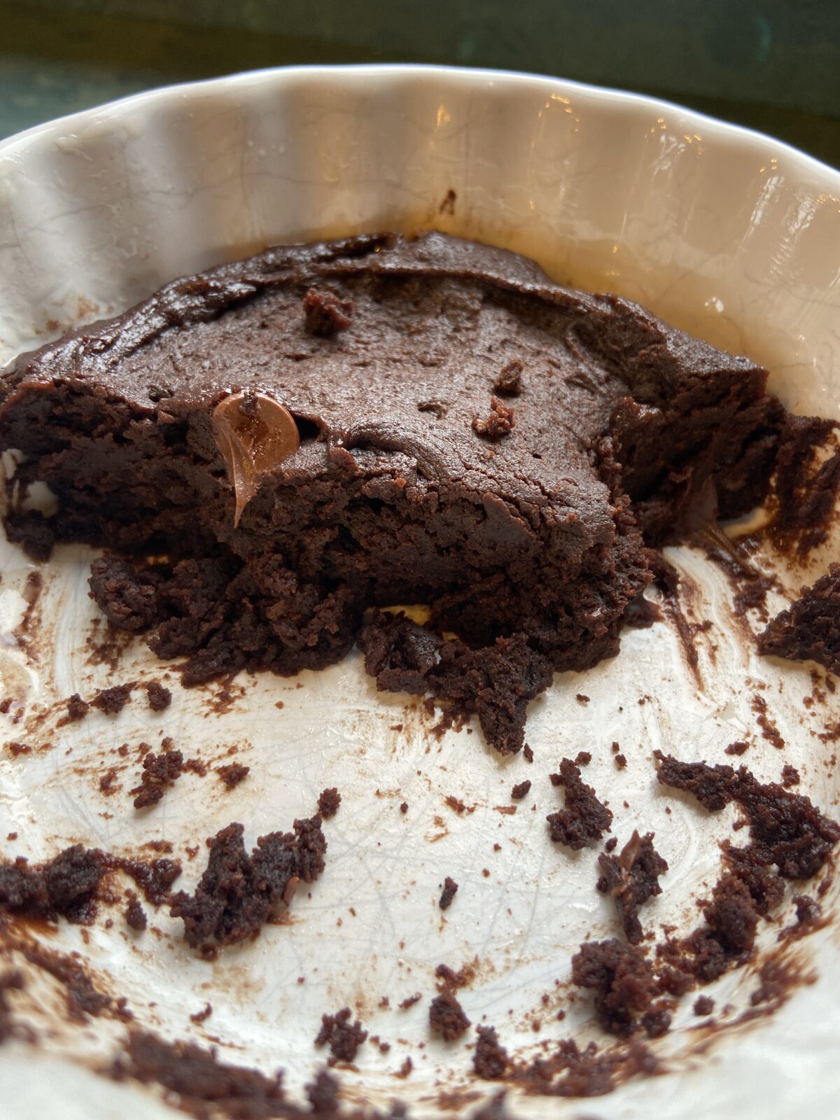 A partially eaten chocolate dessert with a rich, dark texture in a white ceramic dish.