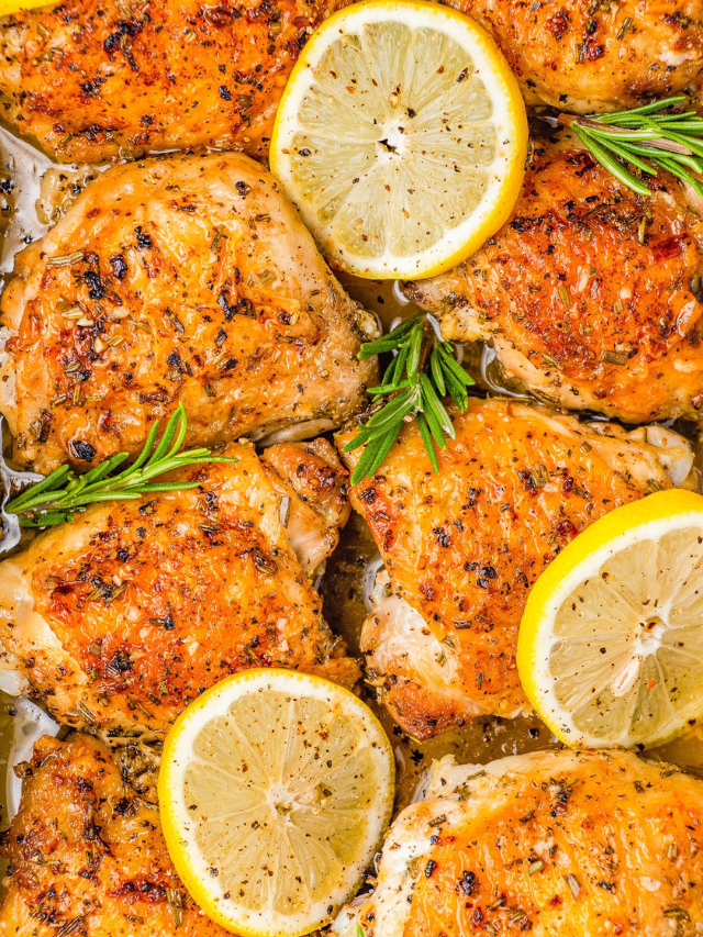 Roasted chicken thighs garnished with lemon slices and sprigs of rosemary.