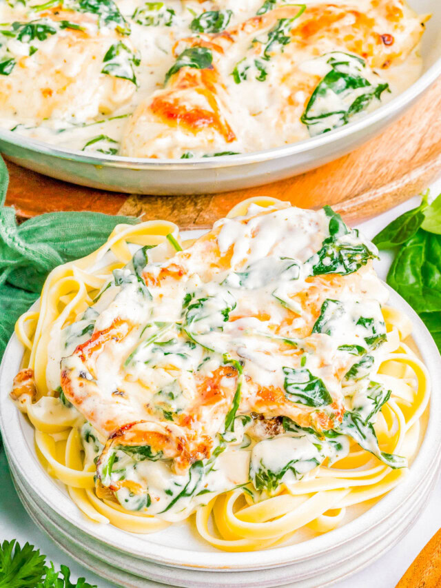 Plate of fettuccine pasta topped with a creamy spinach and cheese sauce, garnished with herbs. A serving dish of the same sauce is in the background.