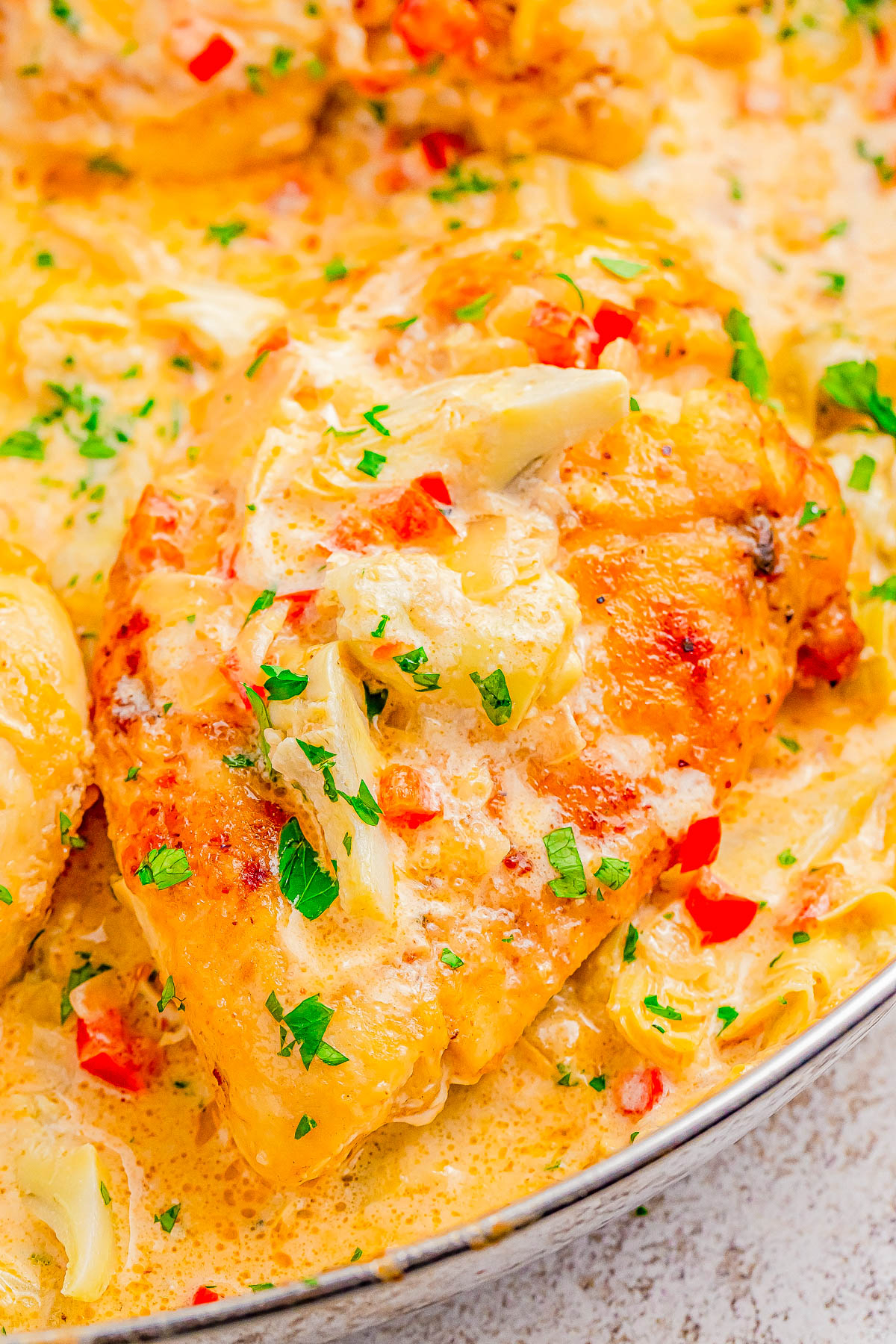 Creamy Parmesan Lemon Chicken Skillet - 🧀🍋🙌🏻 A decadent tasting yet FAST and EASY chicken skillet recipe that's sure to impress your family and friends! Tender lemony chicken, onions, red bell peppers, artichoke hearts, and melted Parmesan cheese with a rich cream sauce for a winner of a chicken dinner! Made in ONE skillet, ready in 30 minutes, and the perfect recipe to jazz up chicken breasts on busy weeknights!