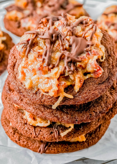 Close-up of a stack of German chocolate cookies topped with caramel, coconut, and a drizzle of chocolate.