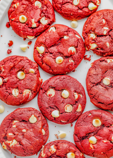 A white plate containing several red velvet cookies with white chocolate chips.