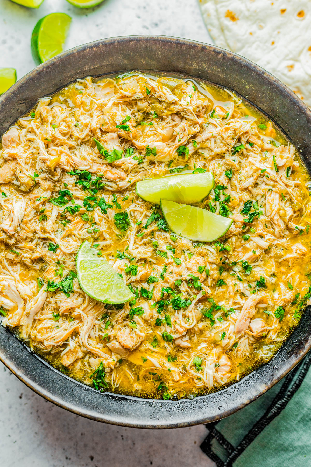 Slow Cooker Green Chile Chicken - Tender, juicy, chicken that's simmered with green chiles, jalapeno, salsa verde, onions, garlic, and spices for the most FLAVORFUL and versatile green chile chicken! Use it in tacos, burritos, casseroles, sandwiches, or as a meal prep recipe. Best of all, it's SO EASY because your slow cooker does ALL the work!