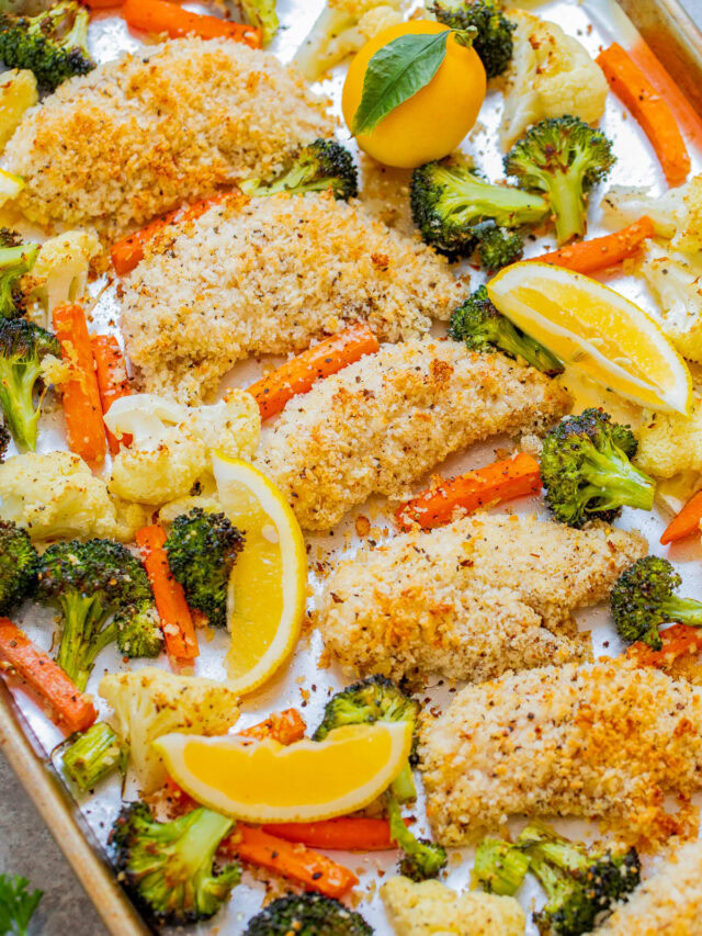 Sheet pan meal of lemon-baked chicken with breaded coating, surrounded by roasted vegetables including broccoli, carrots, and cauliflower, garnished with lemon wedges.