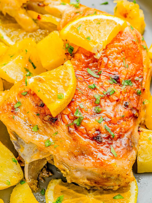 Roasted chicken with crispy skin, garnished with lemon slices and herbs, surrounded by roasted potato chunks.