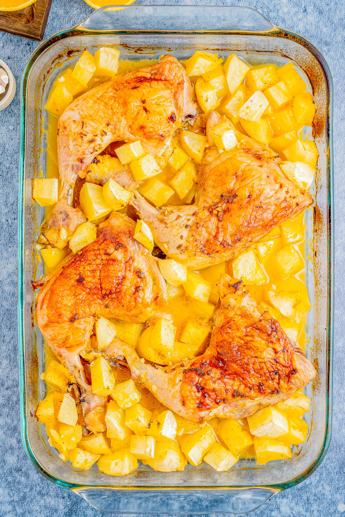 Baked chicken legs with roasted potatoes in a glass dish.