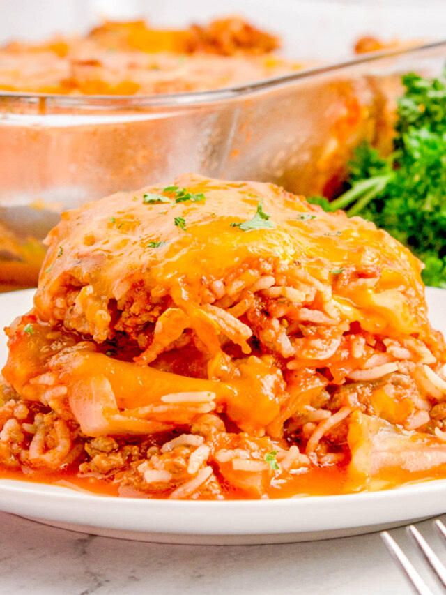 Close-up of a plate with a serving of cheesy beef and rice casserole, garnished with parsley. A glass baking dish with more casserole is visible in the background.