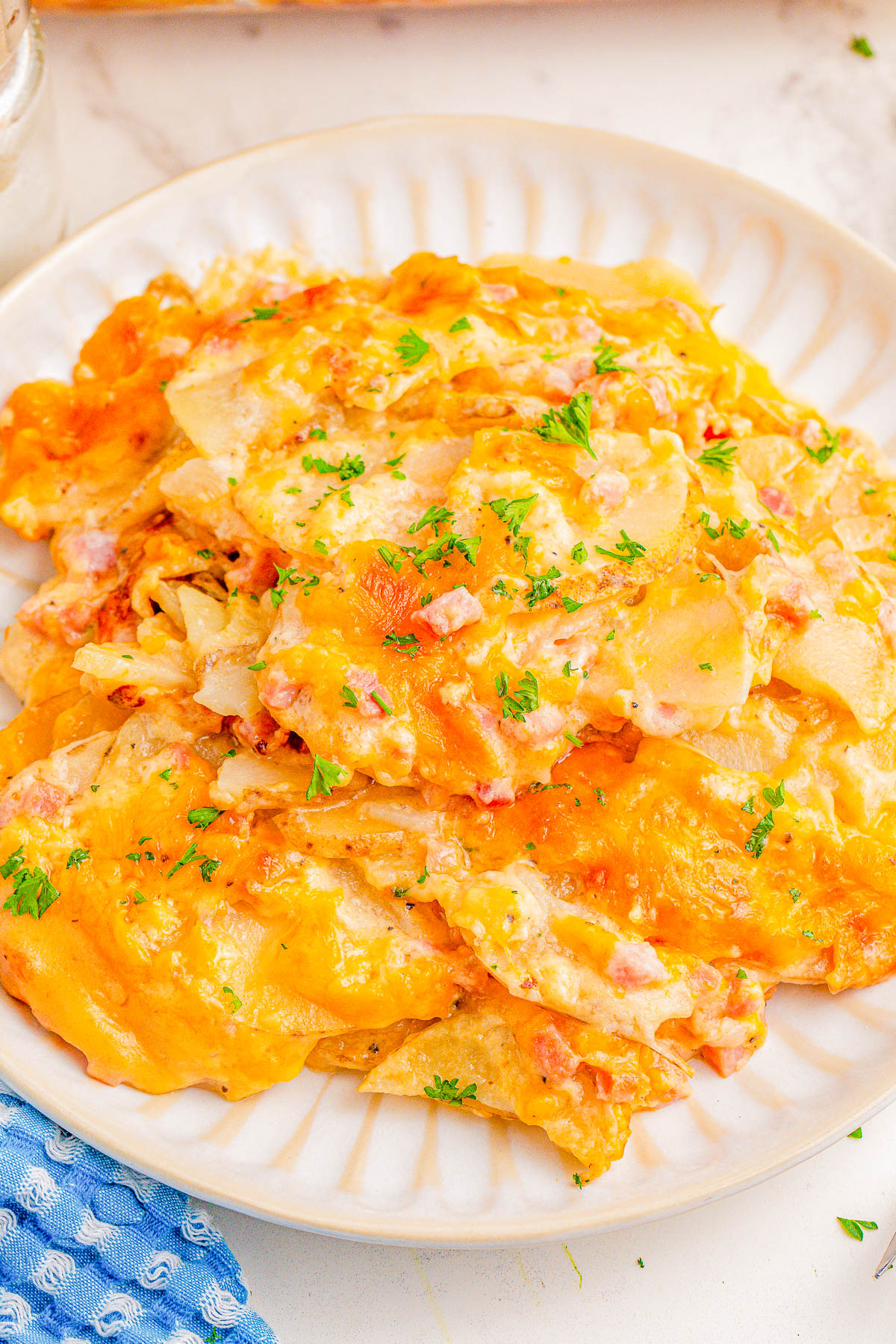 A plate of cheesy scalloped potatoes, garnished with parsley, on a white dish.