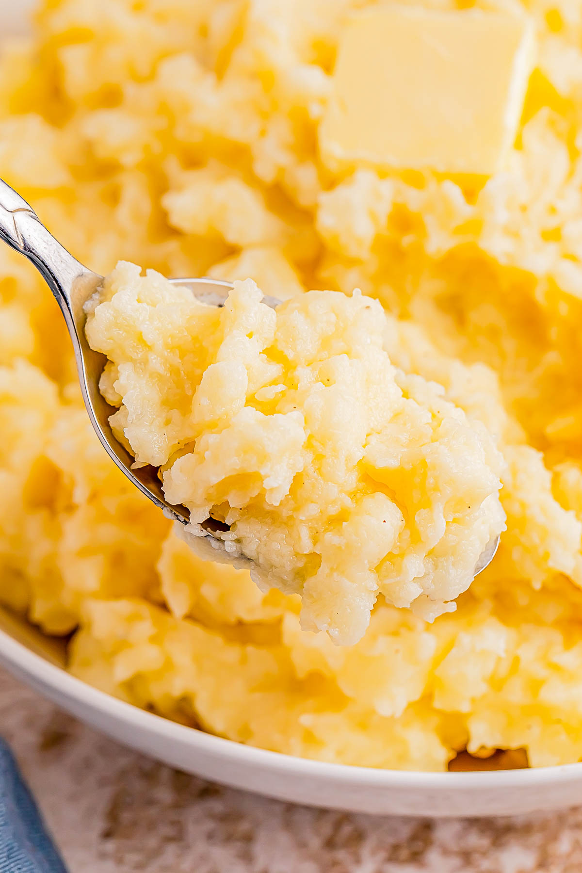 A spoonful of mashed potatoes with a pat of butter in a bowl.