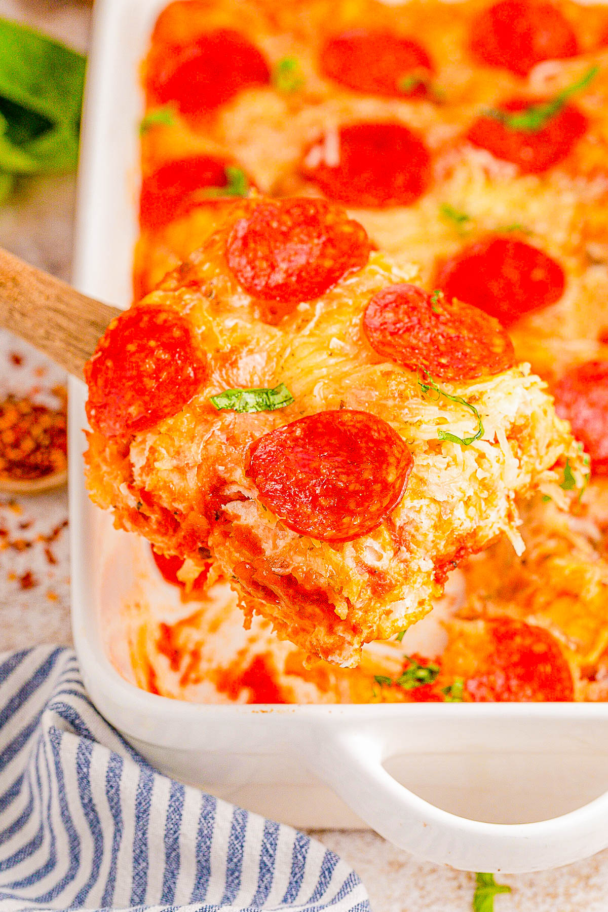 Slice of pepperoni pizza casserole being served from a baking dish.