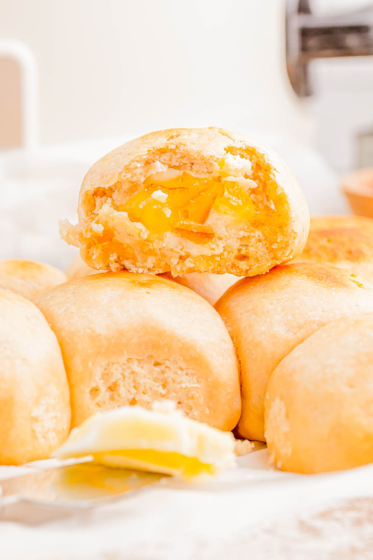 A small stack of golden-brown buns, with one bun torn open to reveal a yellow filling. A spoon with a small amount of filling is in the foreground.