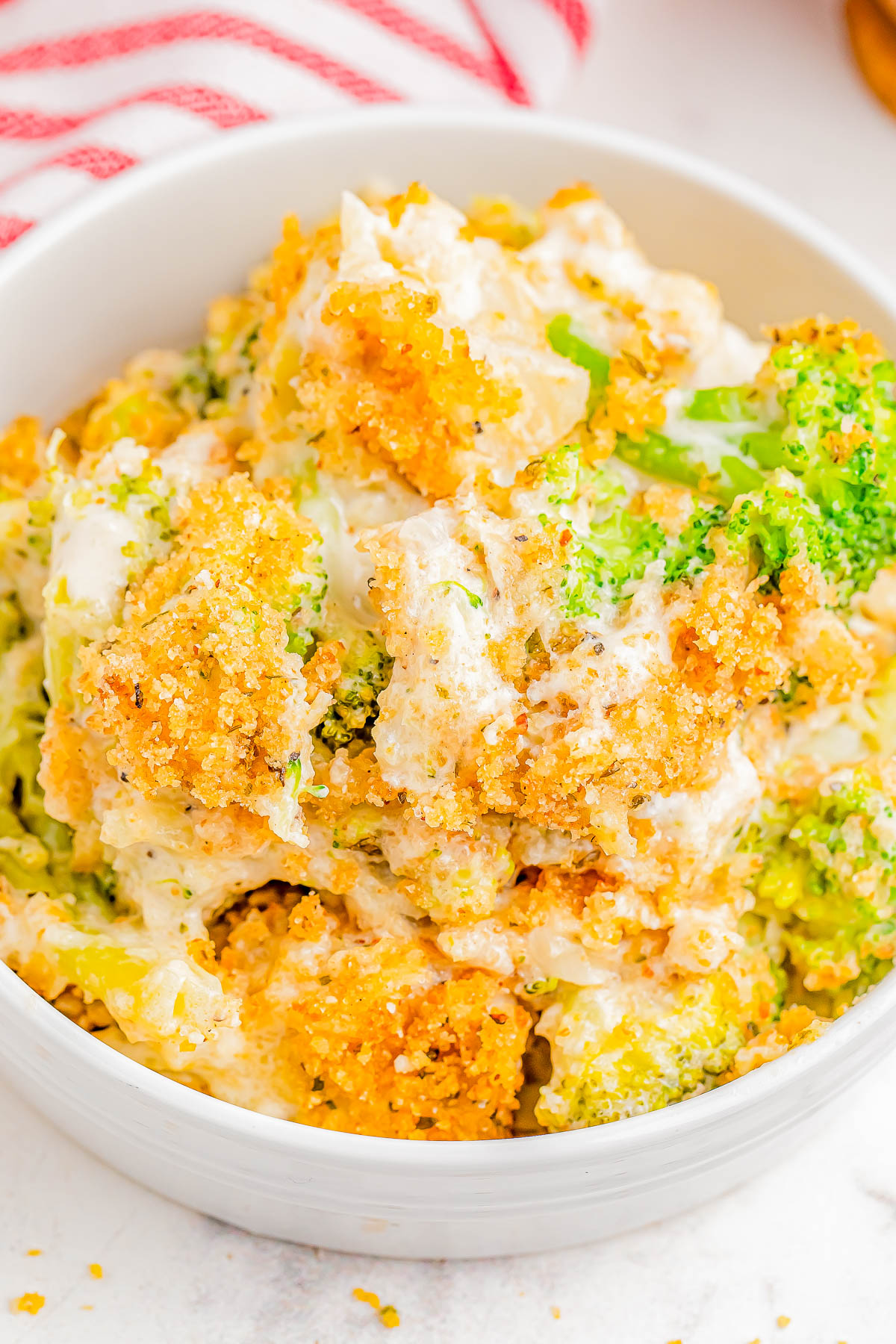 A bowl of cheesy broccoli casserole topped with breadcrumbs.