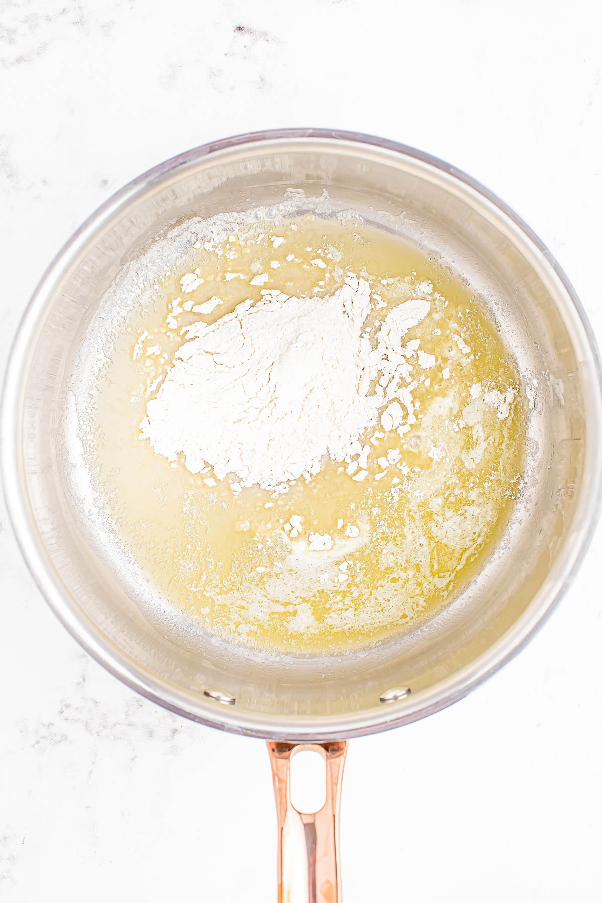 Flour and melted butter mixture in a saucepan, forming the base for a roux.