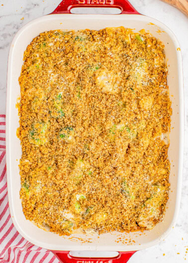 Baked casserole in a rectangular dish with a breadcrumb topping, placed on a marble countertop next to a red-striped cloth.