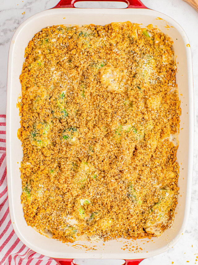 Baked casserole in a rectangular dish with a breadcrumb topping, placed on a marble countertop next to a red-striped cloth.