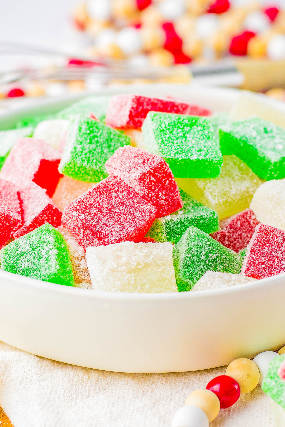 A bowl filled with sugar-coated gummy candies in red, green, and white.