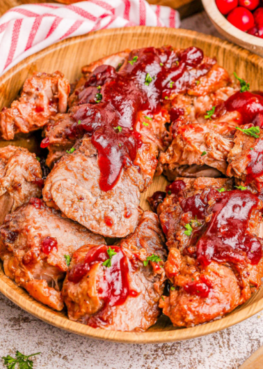 Sliced meatloaf topped with red sauce, garnished with parsley, served on a wooden plate.