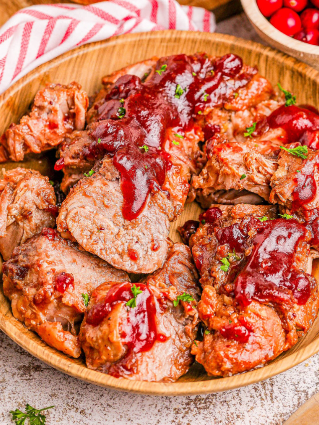 Sliced meatloaf topped with red sauce, garnished with parsley, served on a wooden plate.