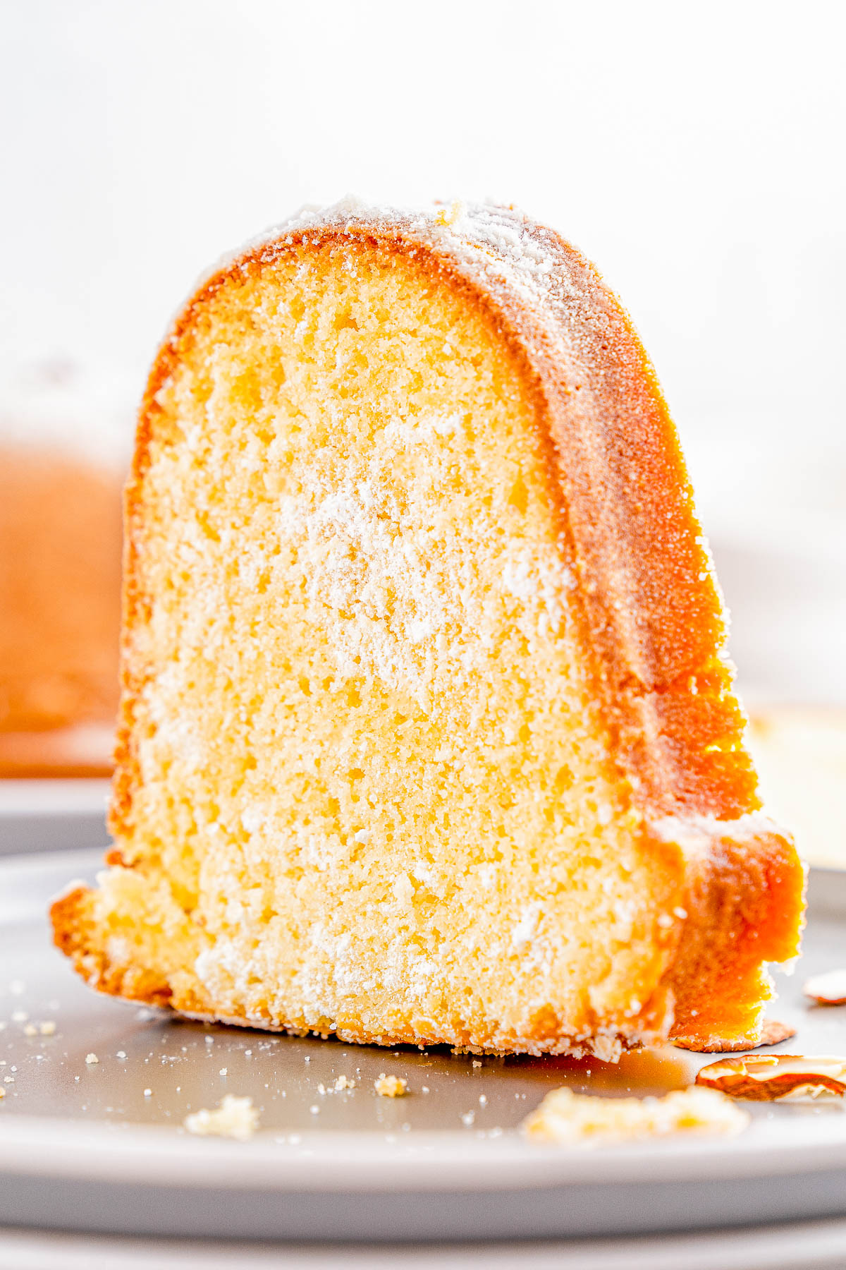 A slice of bundt cake dusted with powdered sugar on a gray plate.