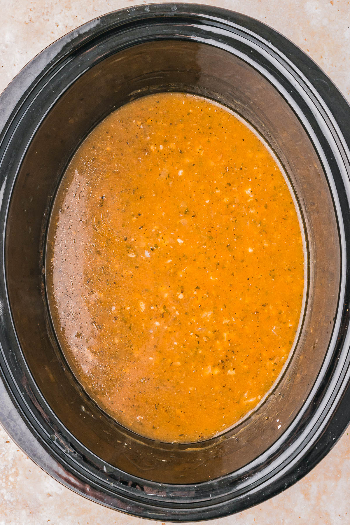 A slow cooker filled with a thick, orange-brown soup.